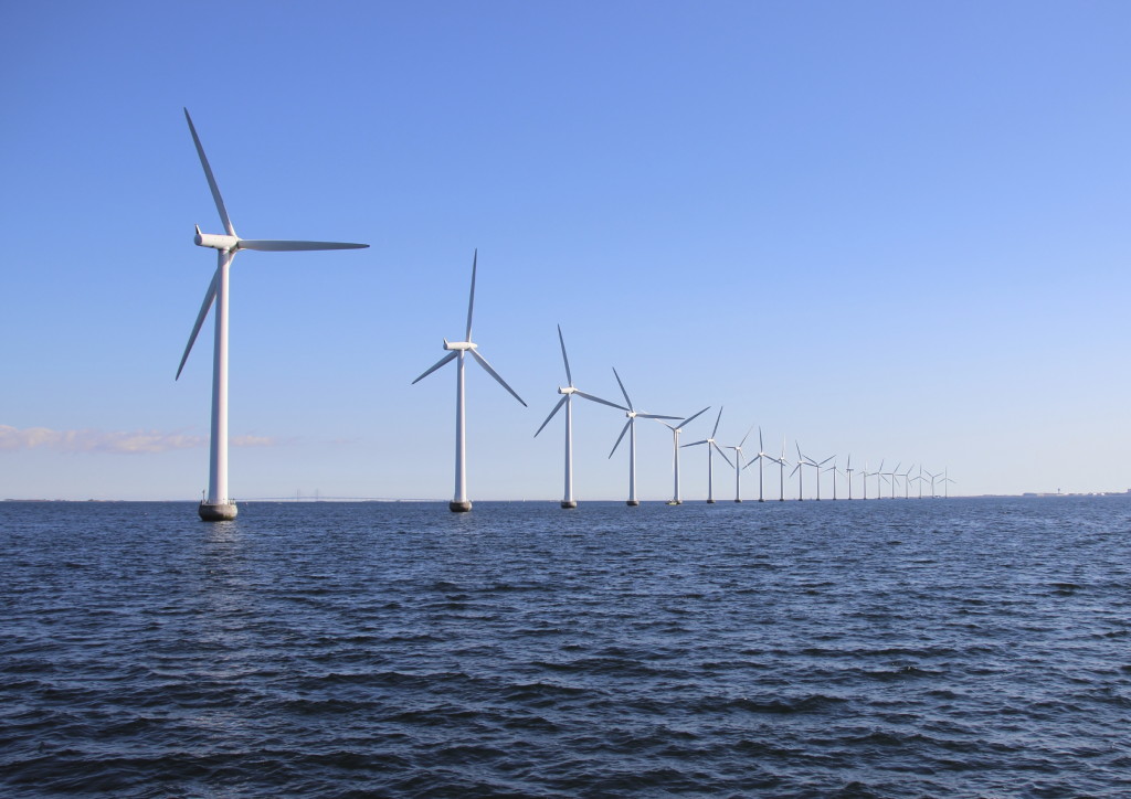 Perspective line of ocean wind mills with dark water and sky