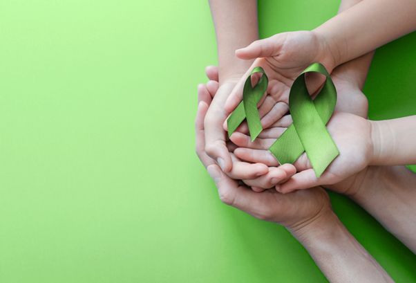 Image Meta Tag: Two pairs of hands holding green mental health ribbon